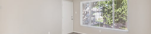 an empty living room with a large window and carpeting
